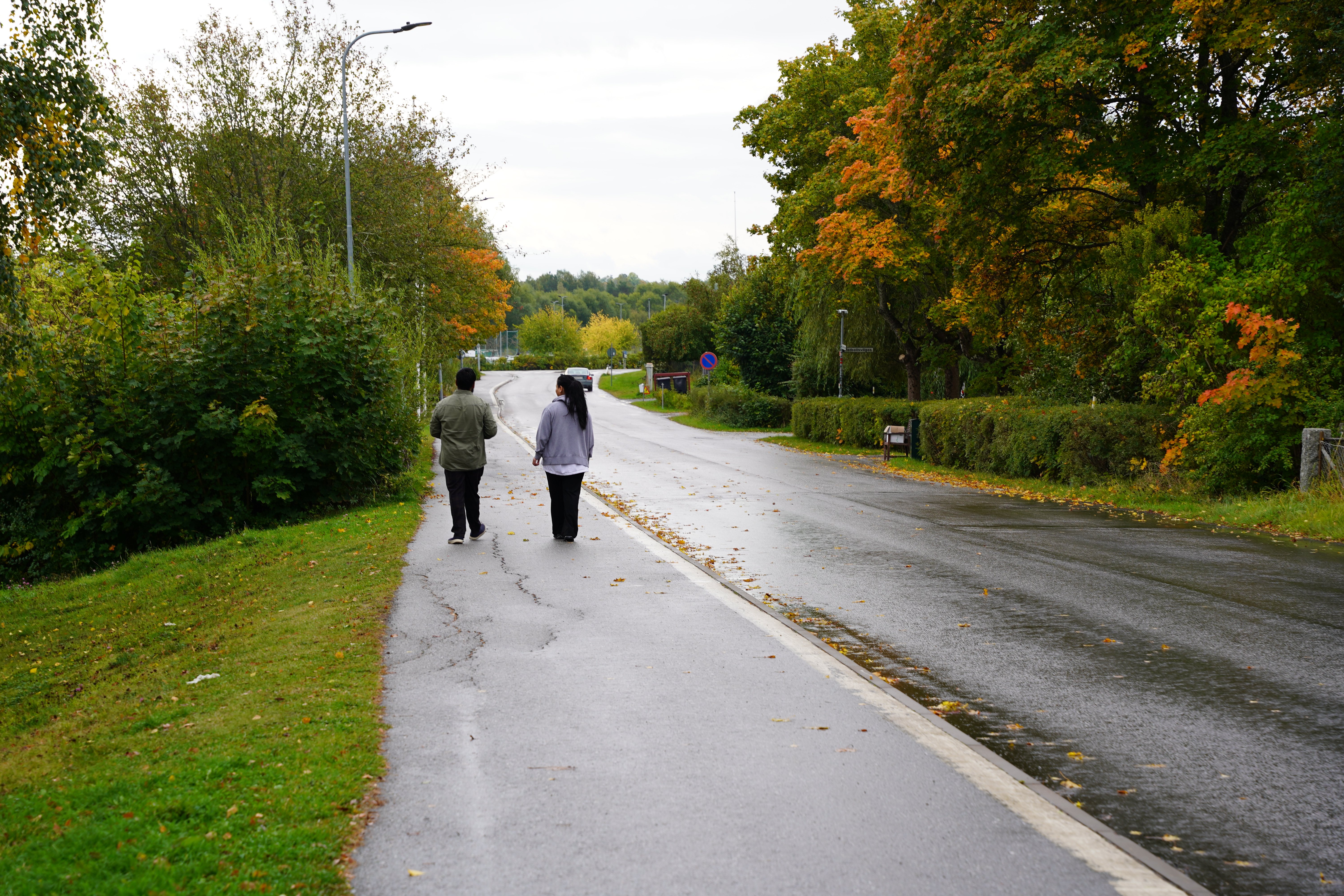 En behandlare och en flicka promenerar p&aring; regnig v&auml;g, samtalar