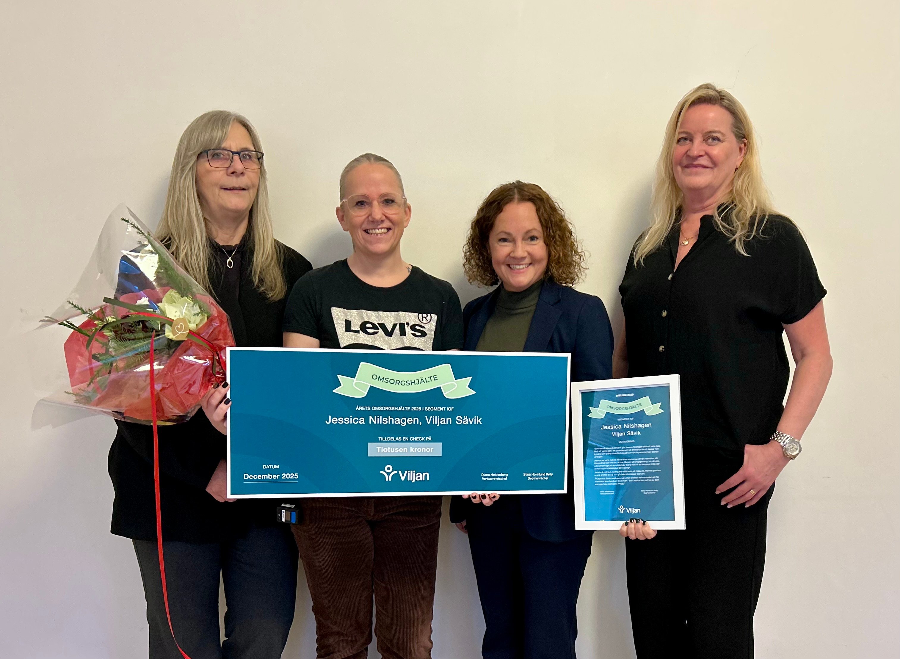 Omsorgshjälten Jessica håller i sin check, omringad av chefer från Viljan som presenterade priset