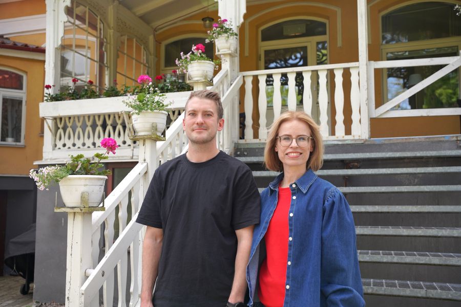 Personal på Viljan Gamla Torg framför ett charmigt hus med trappor och blommor på verandan i en somrig miljö
