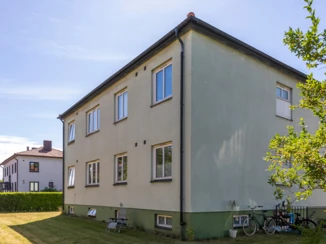 Tvåvåningshus i ett lugnt bostadsområde med grönska och cyklar parkerade utanför