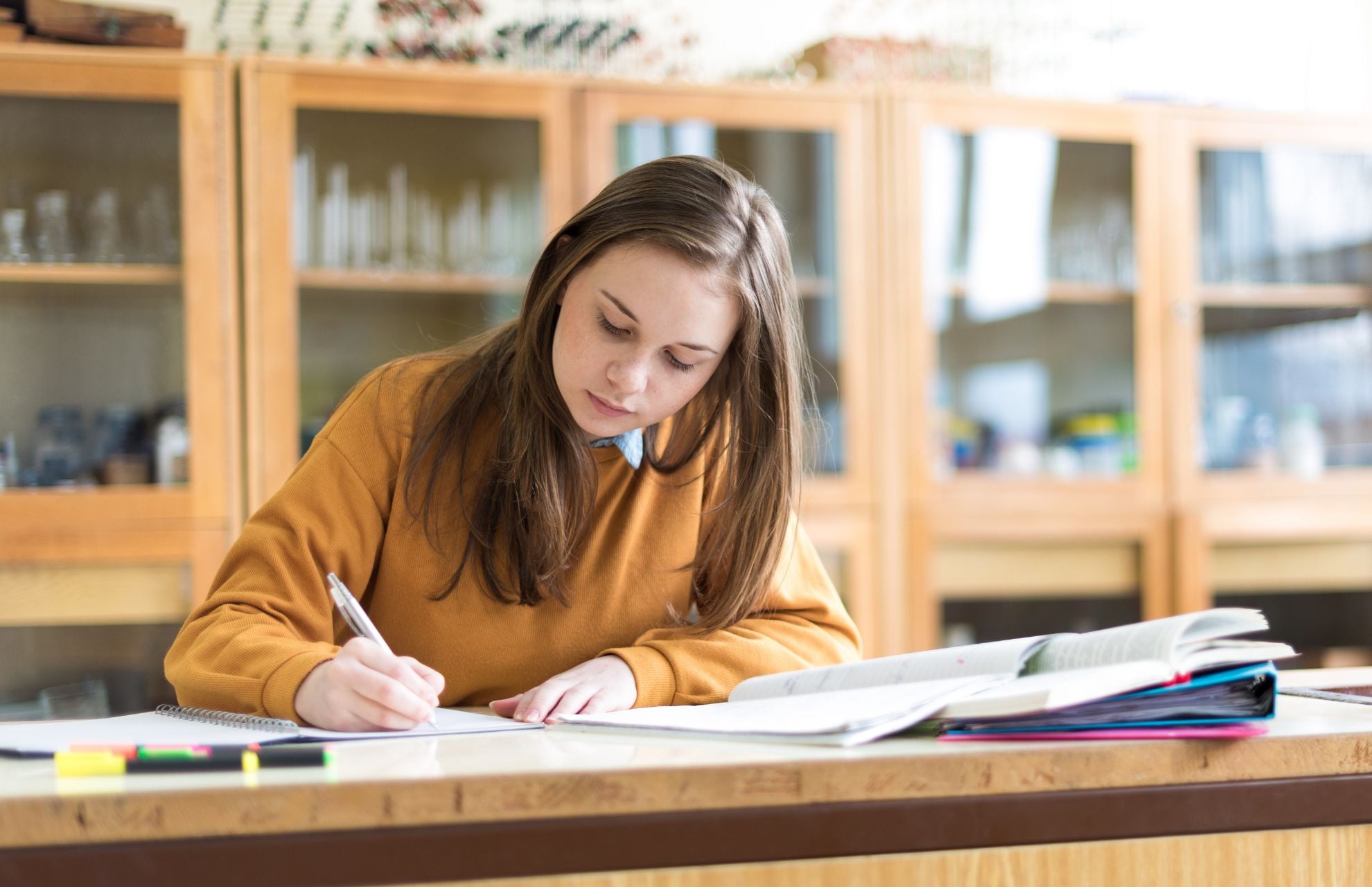 Tjej sitter i skolbibliotek och pluggar