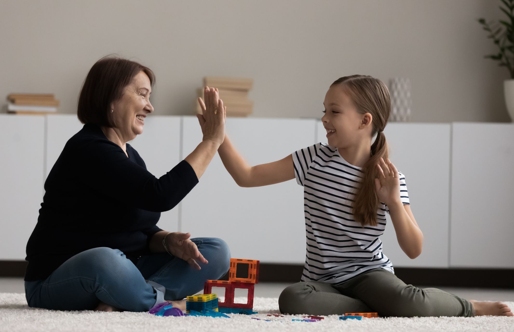 Kvinna och flicka som sitter på golvet high five-ar varandra