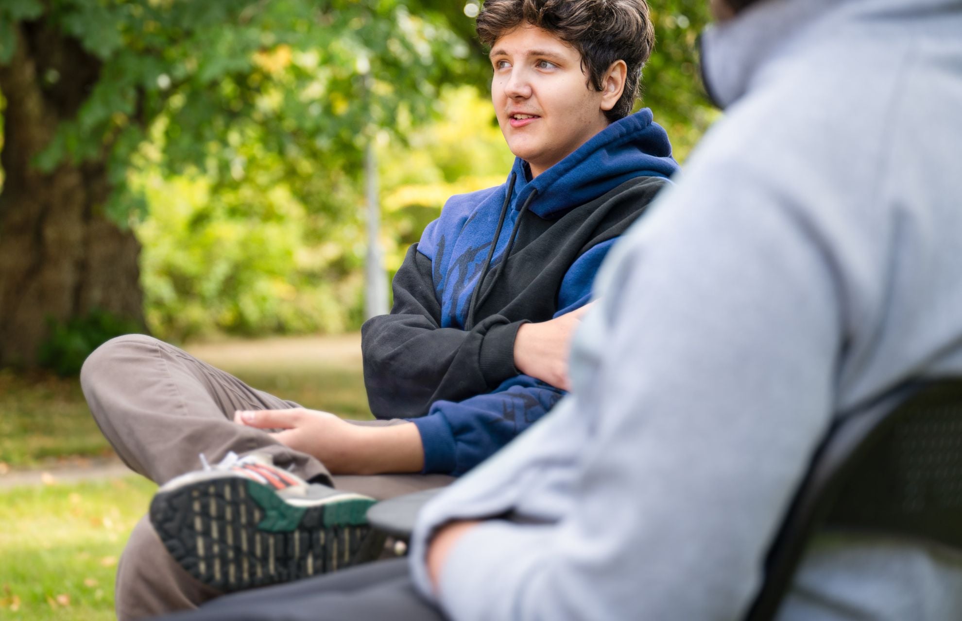Elev p&aring; skolan i samtal med en vuxen, sitter ute i gr&ouml;nska