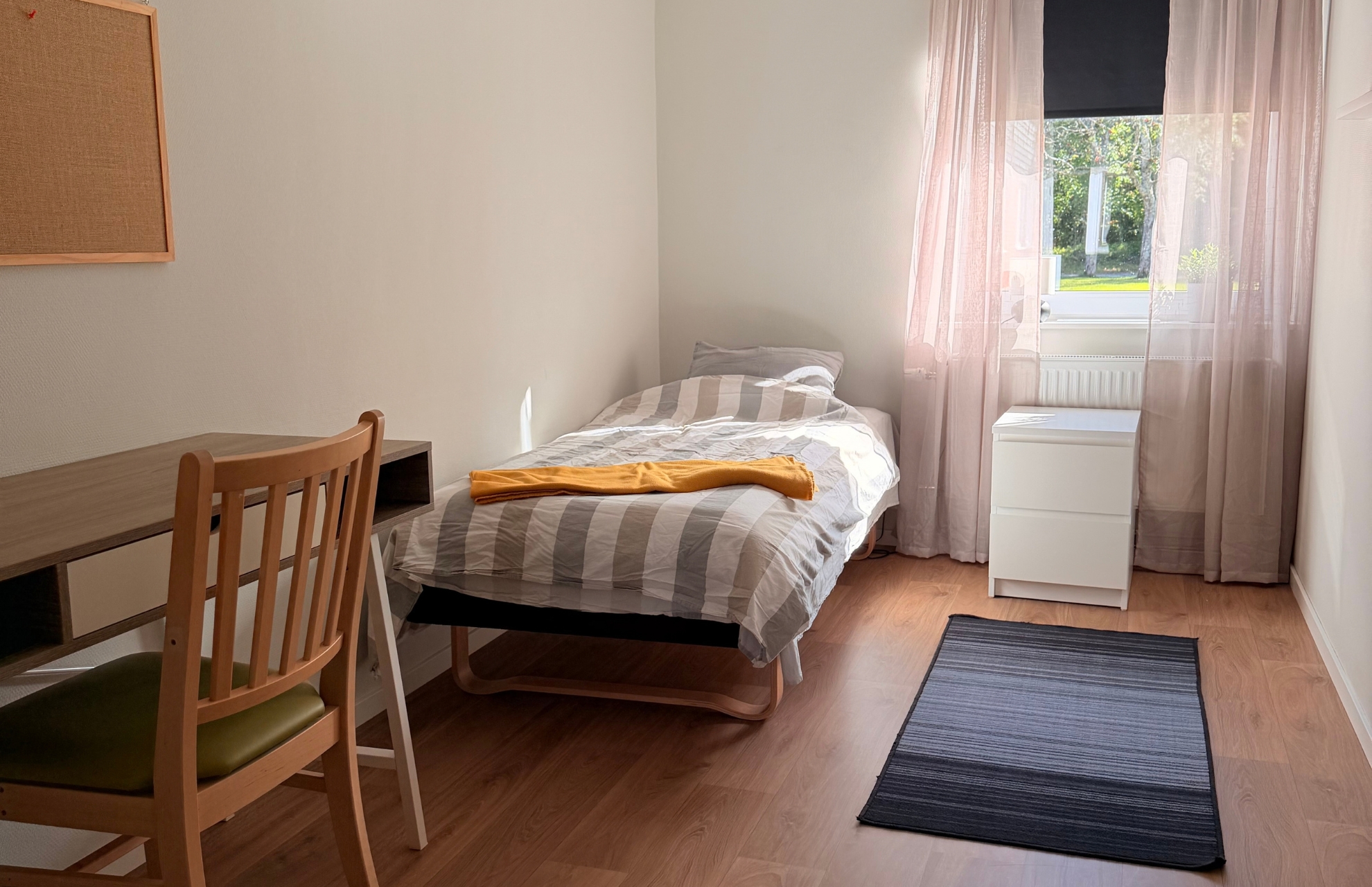 Sovrum med säng, skrivbord, fönster, matta